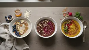 Tre ciotole di porridge con frutta, semi e spezie su un tavolo: banana e mirtilli, cacao e frutti rossi, curcuma e melograno