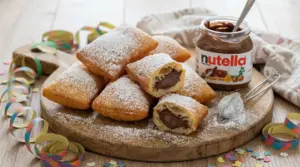 Bugie di Carnevale ripiene di Nutella, fritte e spolverate di zucchero a velo su tagliere di legno