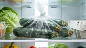 Zucchine crude chiuse in un sacchetto di plastica nel frigorifero con condensa all'interno