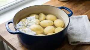Patate pelate immerse in acqua fredda in una pentola, pronte per la cottura