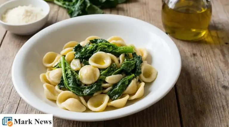 Piatto di orecchiette con cime di rapa in una ciotola bianca, su tavolo di legno con olio extravergine d’oliva