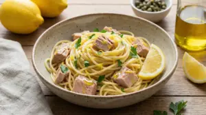 Spaghetti al tonno e limone con prezzemolo e scorza di limone, serviti in una ciotola con spicchi di limone