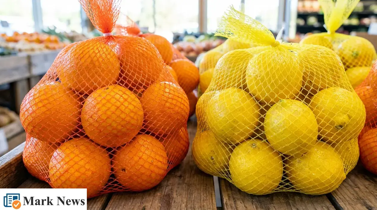 Reti arancioni con arance e reti gialle con limoni esposte su un banco di frutta al supermercato