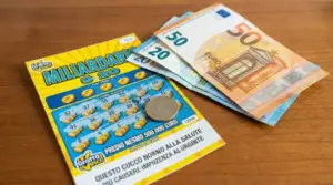 Gratta e vinci su un tavolo con banconote in euro e una moneta, tema tasse sulle vincite